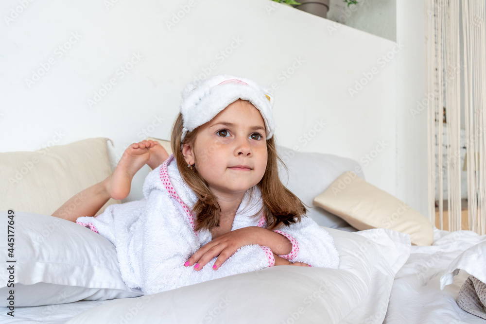 Daughter are dressed in white terry robes, lie on the bed. Nursing communication in the family. Daughter are dressed in white terry robes, lie on the bed. Nursing communication in the family.
