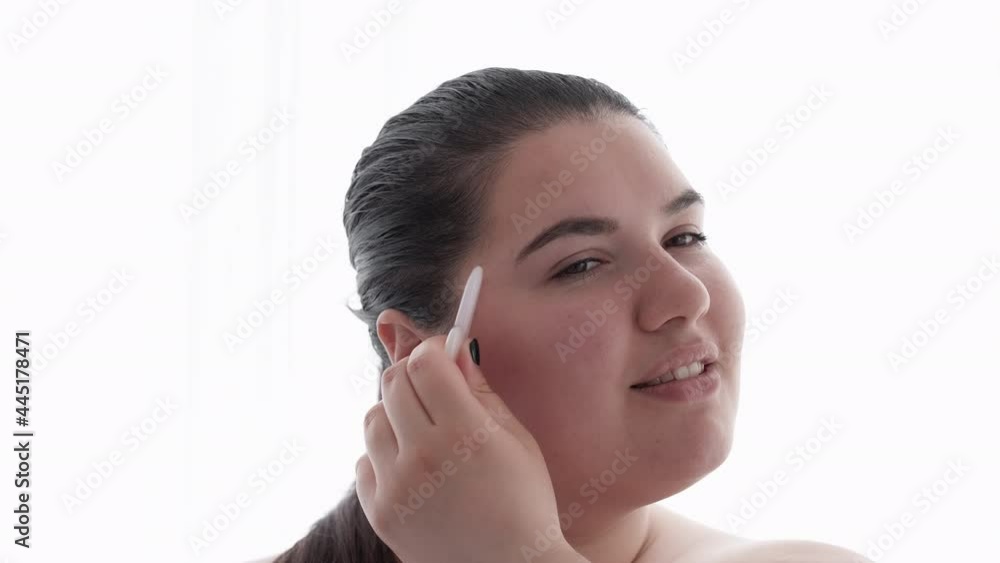 Gua sha skincare. Facial acupressure. Skin elasticity. Body positive. Facelift treatment. Overweight obese woman enjoying doing face massage with quartz tool isolated on white. Gua sha skincare. Facial acupressure. Skin elasticity. Body positive. Facelift treatment. Overweight obese woman enjoying doing face massage with quartz tool isolated on white.