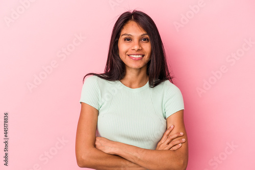 Young latin woman isolated on pink background who feels confident, crossing arms with determination.