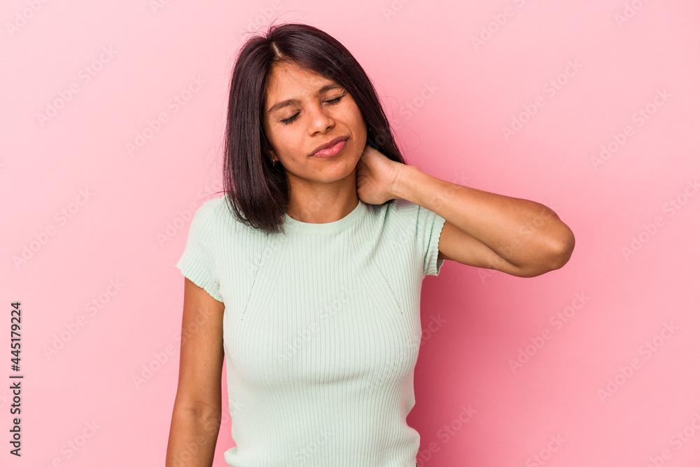 Fototapeta premium Young latin woman isolated on pink background having a neck pain due to stress, massaging and touching it with hand.