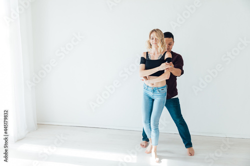 beautiful man and woman dancing together to music in a white room