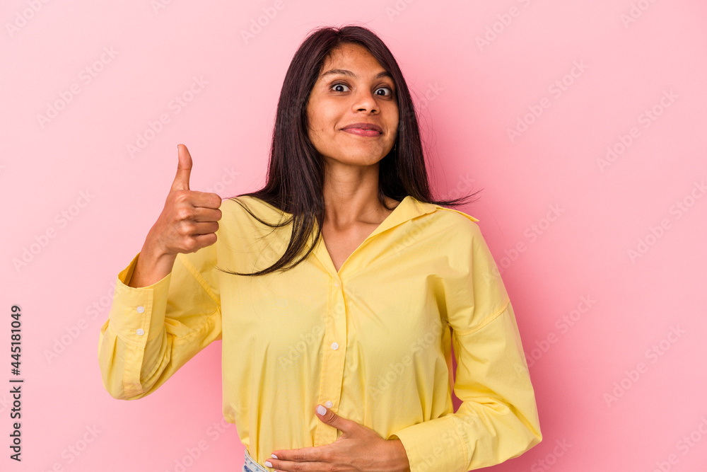 Young latin woman isolated on pink background touches tummy, smiles gently, eating and satisfaction concept. Young latin woman isolated on pink background touches tummy, smiles gently, eating and satisfaction concept.