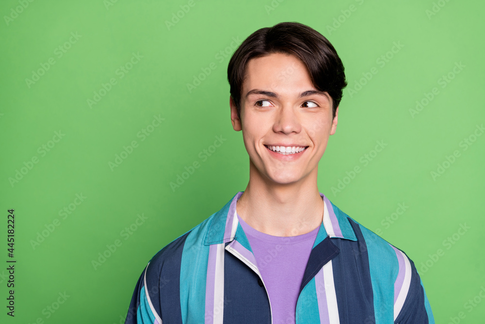 Photo of funny brunet millennial guy look empty space wear blue shirt isolated on green color background Photo of funny brunet millennial guy look empty space wear blue shirt isolated on green color background