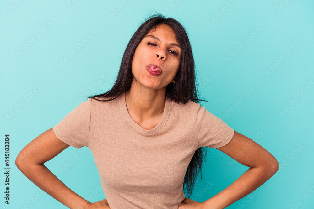 Young latin woman isolated on blue background funny and friendly sticking out tongue. Young latin woman isolated on blue background funny and friendly sticking out tongue.