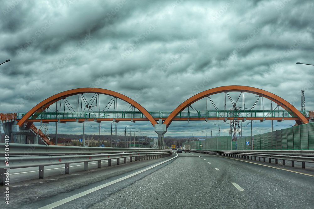 The bridge across the road, there are clouds in the sky. Without people