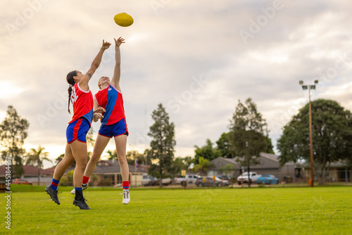 two footy players stretching up to tap the ball away