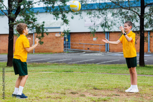 Two Aussie school boys throwing a ball together outside photo