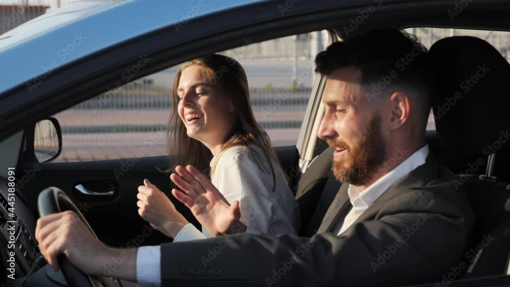 Profile of young man driver with wife dancing singing songs having fun in a car before the driving at sunset. People feeling joyful excited. Transport passengers concept. Shooting made outside auto. Profile of young man driver with wife dancing singing songs having fun in a car before the driving at sunset. People feeling joyful excited. Transport passengers concept. Shooting made outside auto.