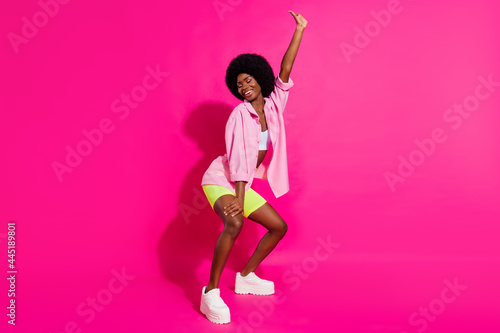Photo of pretty charming dark skin lady wear casual shirt dancing twerk smiling isolated pink color background photo