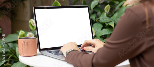 Woman using or typing laptop outside cafe restaurant with natural. Laptop computer on white desk and white blank on screen.