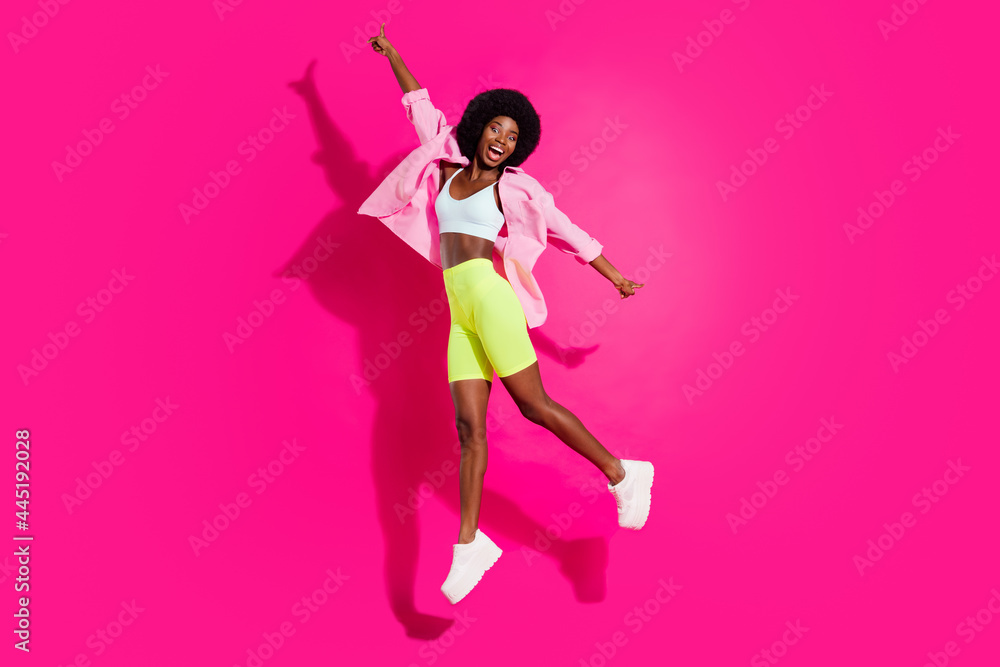 Full length profile side photo of young excited african girl happy positive smile jump up isolated over pink color background Full length profile side photo of young excited african girl happy positive smile jump up isolated over pink color background