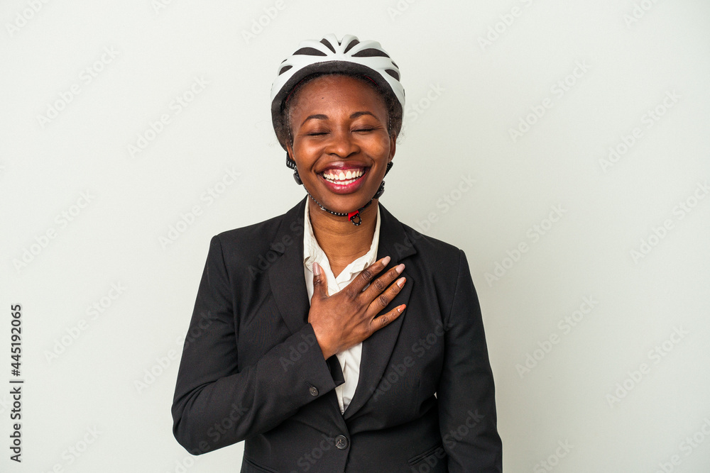 Young business african american woman wearing a bike helmet isolated on white background laughs out loudly keeping hand on chest. Young business african american woman wearing a bike helmet isolated on white background laughs out loudly keeping hand on chest.