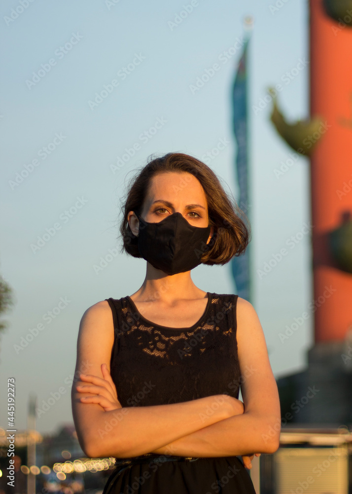 young woman in mask on face standing crossing arms, protest against isolation due to covid-19