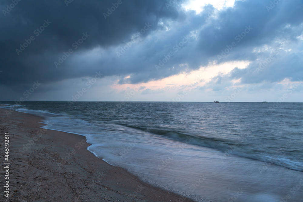 Thunderous gloomy clouds on the sea coast before dawn