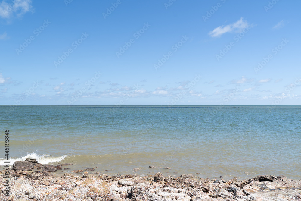 Picture of a beach with sea and bright blue sky.