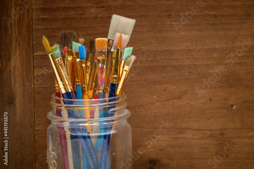 A jar of brushes sit on a shelf in an artists studio