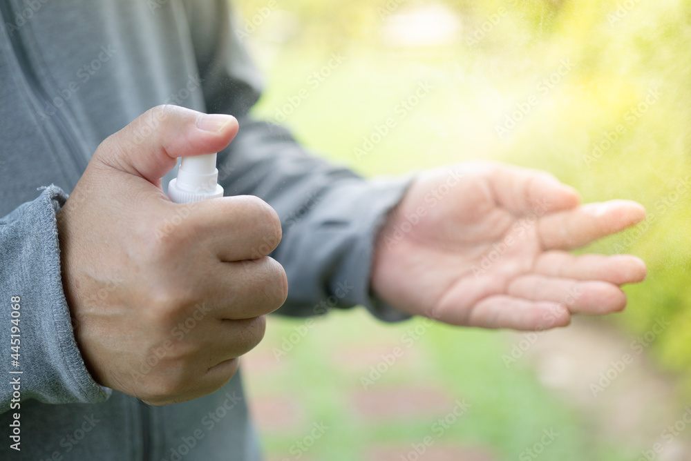 Fototapeta premium Asian man spray wipes his hands with an alcohol-based hand-washing spray as a preventive hygiene measure against coronavirus infection Antibacterial hand sanitizer gel New normal life style Covid-19