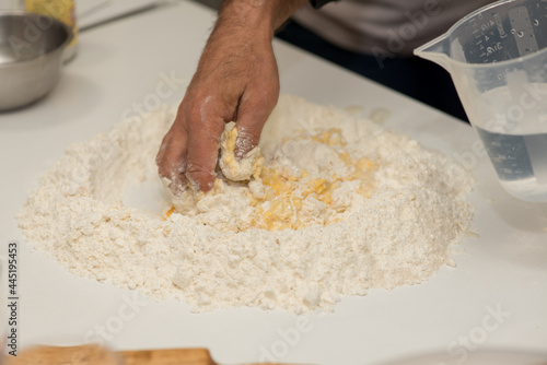 Flour and eggs. Hands kneading dough on board - flour and eggs. Selective focus. The concept of cooking, alibi, pizza with your own hands