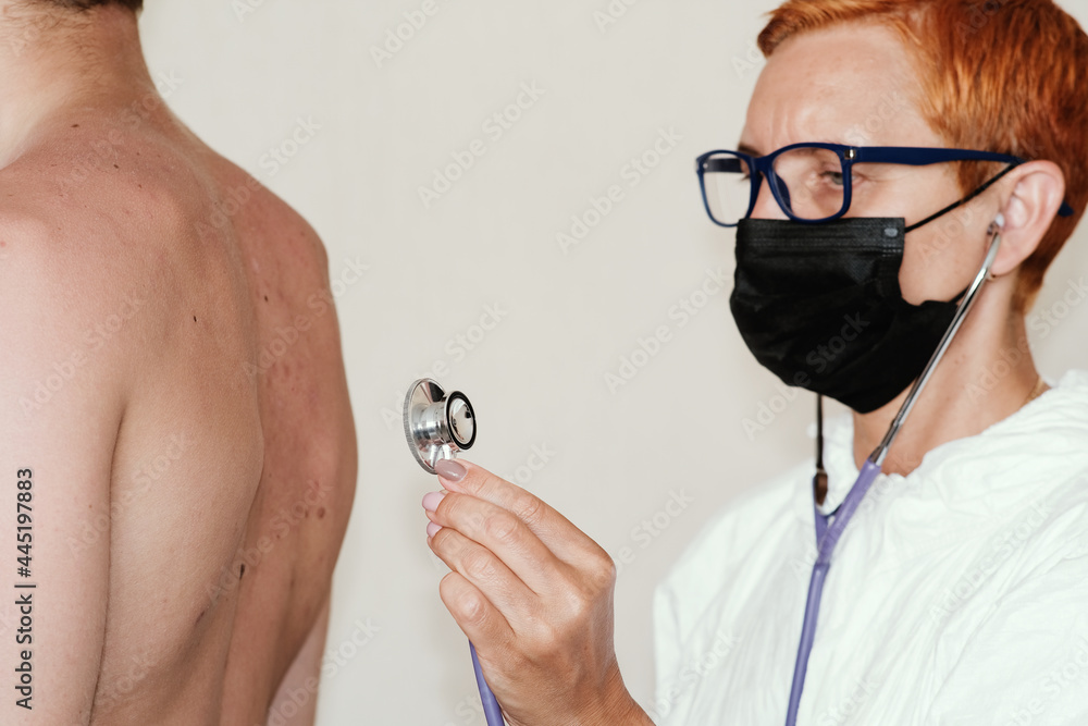 Fototapeta premium A therapist with a stethoscope is preparing to listen to the patient's lung breathing. The concept of rehabilitation after a coronavirus disease.
