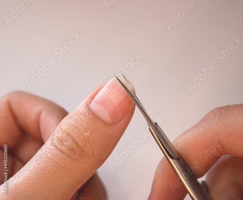 A person cuts his nails with small scissors. Men s manicure. A man cuts off a large overgrown nail