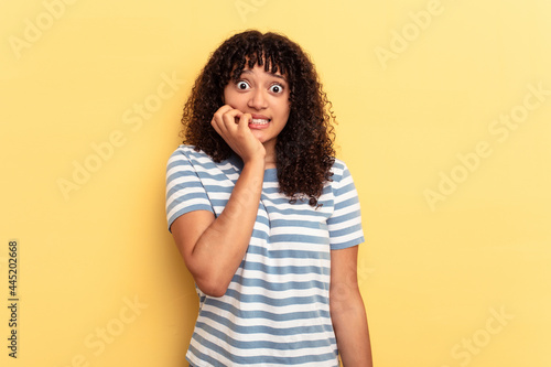 Young mixed race woman isolated on yellow background biting fingernails, nervous and very anxious.