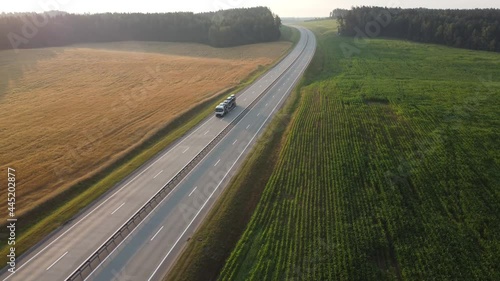 Aerial drone footage: Large car transporter (car hauler) delivery truck is fully loaded on the highway. Transportation of new cars from the factory to the car dealership.