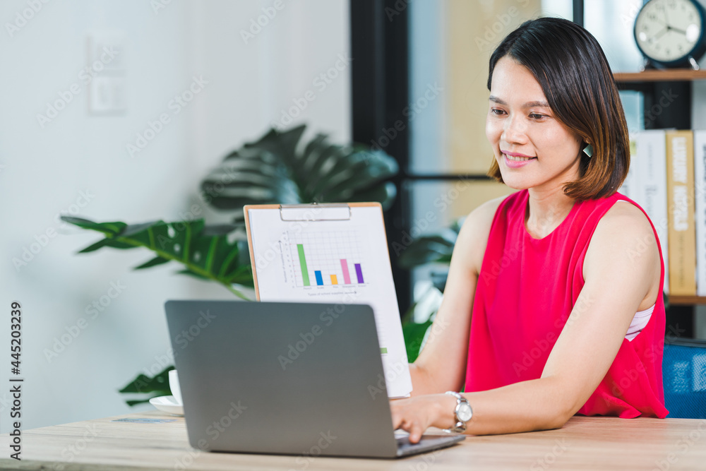 Asian businesswoman presenting business report via video call on a laptop at home. Businessperson or entrepreneur working, online shopping, e-commerce, internet banking, working from home concept Asian businesswoman presenting business report via video call on a laptop at home. Businessperson or entrepreneur working, online shopping, e-commerce, internet banking, working from home concept