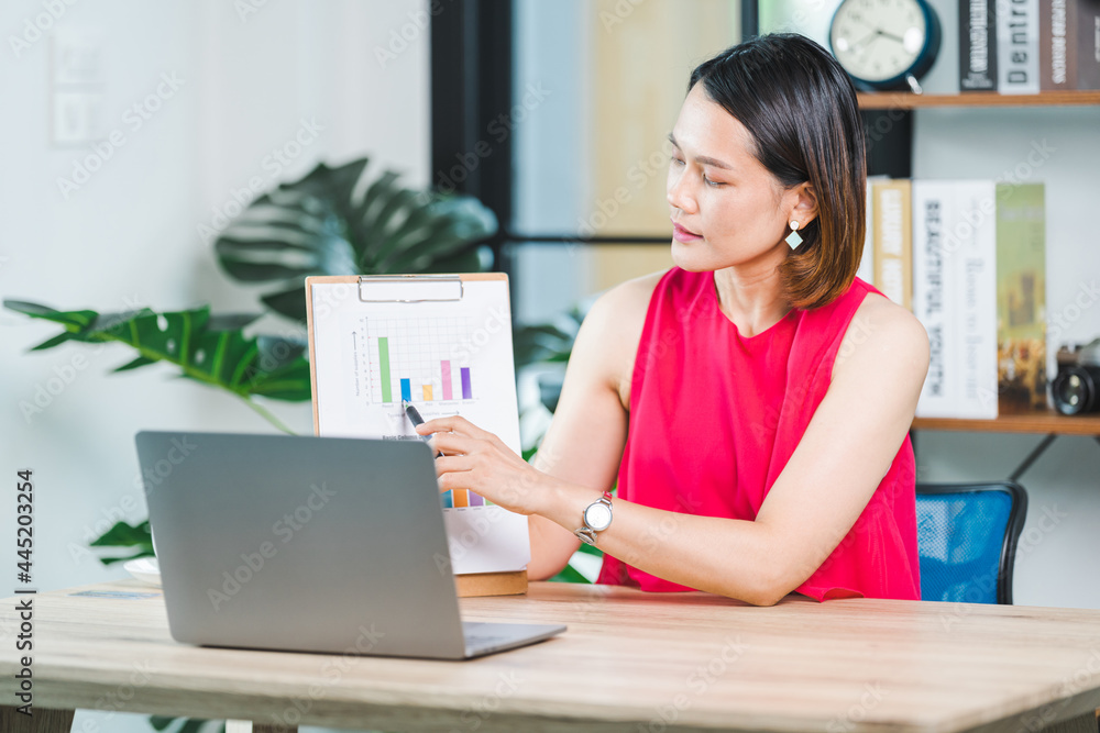Asian businesswoman presenting business report via video call on a laptop at home. Businessperson or entrepreneur working, online shopping, e-commerce, internet banking, working from home concept Asian businesswoman presenting business report via video call on a laptop at home. Businessperson or entrepreneur working, online shopping, e-commerce, internet banking, working from home concept