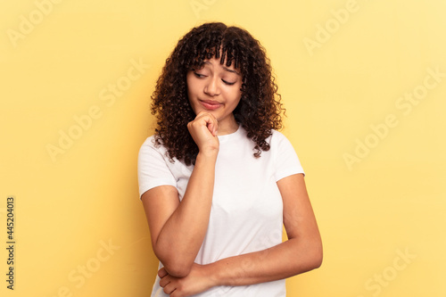 Young mixed race woman isolated on yellow background looking sideways with doubtful and skeptical expression.
