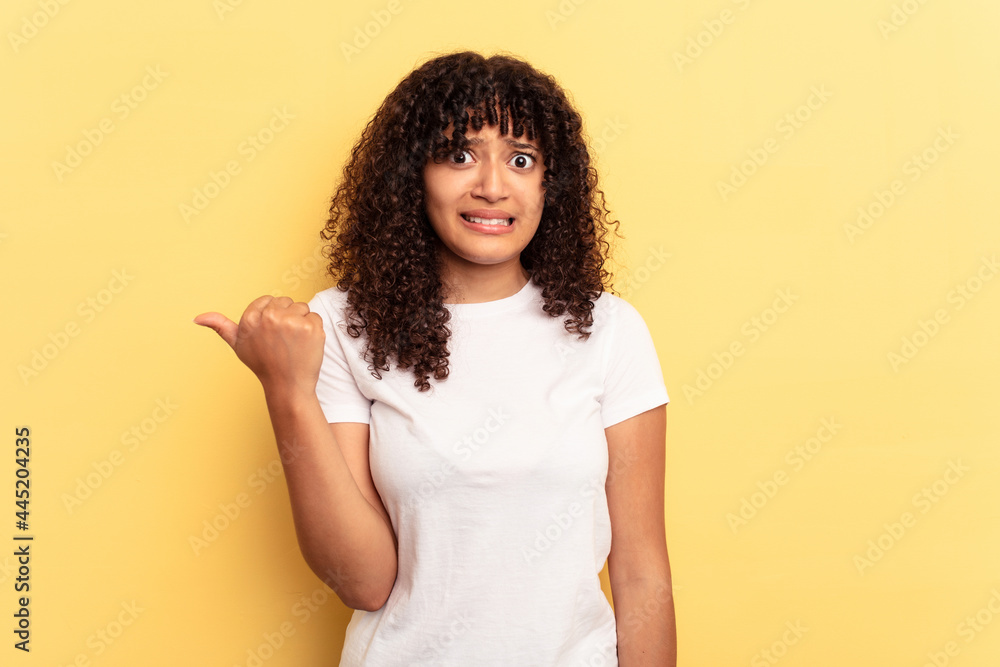 Young mixed race woman isolated on yellow background shocked pointing with index fingers to a copy space.