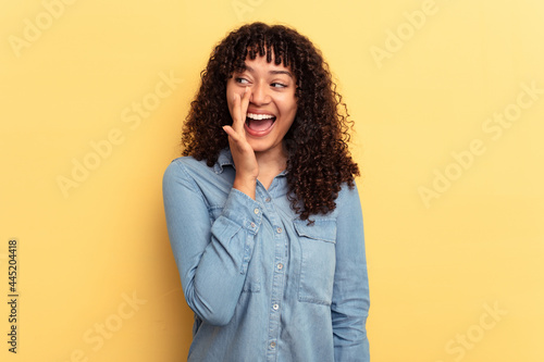 Young mixed race woman isolated on yellow background shouting excited to front.