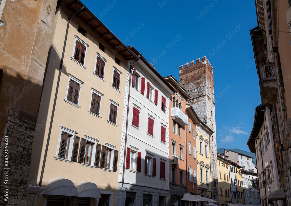 Trento, Italy, June 2021. In the historic center a medieval tower stands out among the brightly colored facades of the houses. Beautiful summer day.