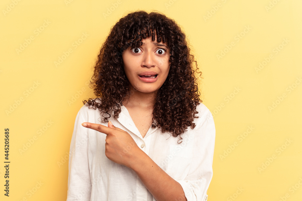 Young mixed race woman isolated on yellow background pointing to the side Young mixed race woman isolated on yellow background pointing to the side