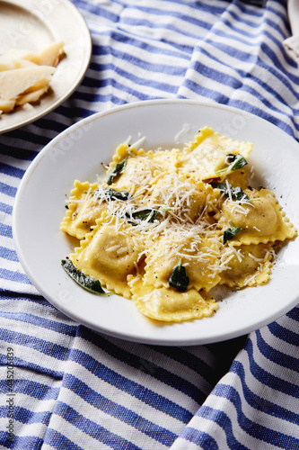 ravioli with butter parmesan and sage dish on a blue stripe tablecloth