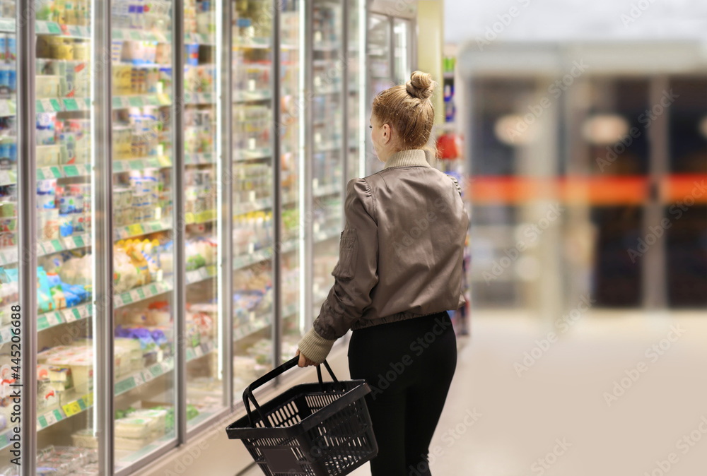 Woman choosing frozen food from a supermarket freezer.. Woman choosing frozen food from a supermarket freezer..