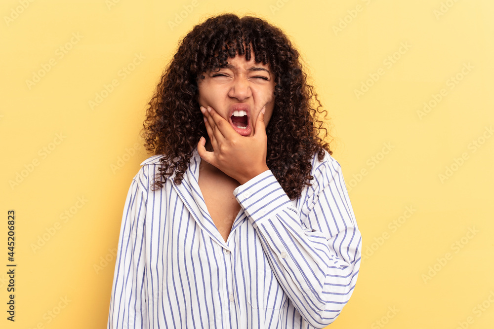 Young mixed race woman isolated on yellow background having a strong teeth pain, molar ache.