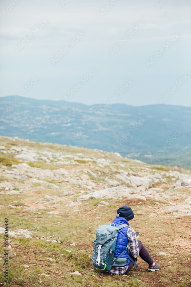 a woman looks at a smartphone on top of a mountain on a hiking trip