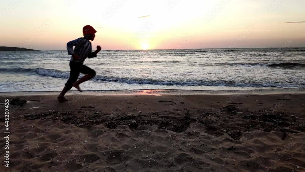 Silhouette of a boy running along the seashore in the evening at sunset, slow motion video. Beautiful sunset with clouds sky. Selective focus. High quality FullHD footage Silhouette of a boy running along the seashore in the evening at sunset, slow motion video. Beautiful sunset with clouds sky. Selective focus. High quality FullHD footage