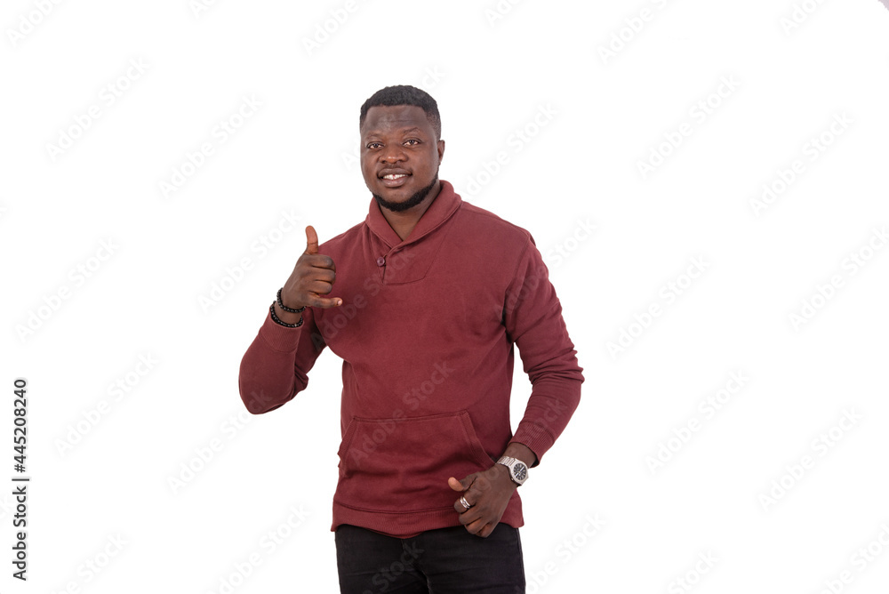 Naklejka premium young man making mobile phone gesture with his fingers smiling.