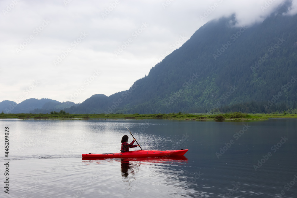Adventure Caucasian Adult Woman Kayaking in Red Kayak surrounded by Canadian Mountain Landscape. Taken in Widgeon Valley, Pitt Meadows, Vancouver, British Columbia, Canada.