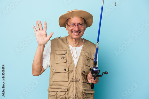 Senior indian fisherman holding rod isolated on blue background smiling cheerful showing number five with fingers.