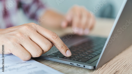 Cropped close-up image of a businessman`s hands typing working on a laptop at the home office. Freelancer, remote occupation, tutor, student e-learning concept