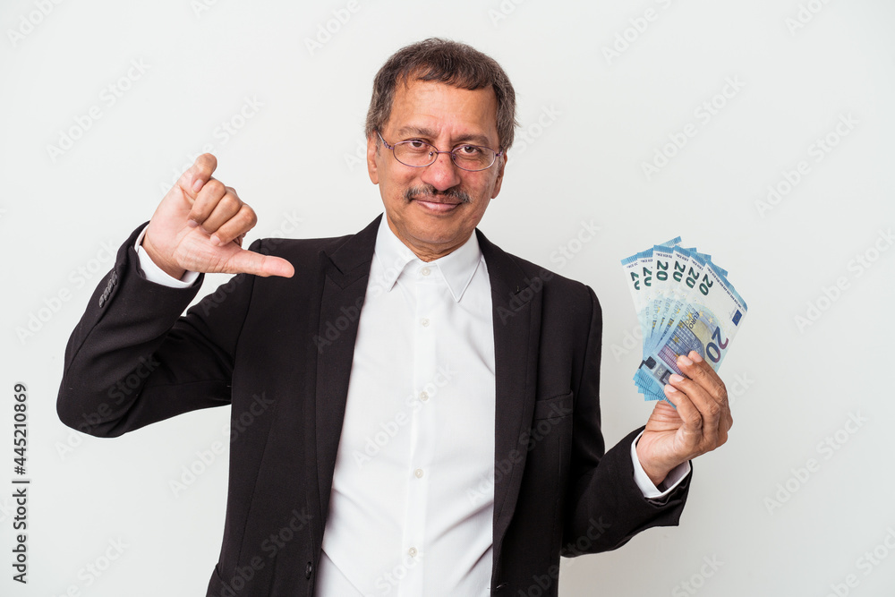 Middle aged indian business man holding bills isolated on white background showing a dislike gesture, thumbs down. Disagreement concept. Middle aged indian business man holding bills isolated on white background showing a dislike gesture, thumbs down. Disagreement concept.