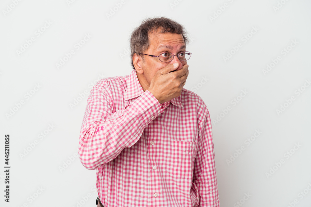Middle aged indian man isolated on white background thoughtful looking to a copy space covering mouth with hand. Middle aged indian man isolated on white background thoughtful looking to a copy space covering mouth with hand.
