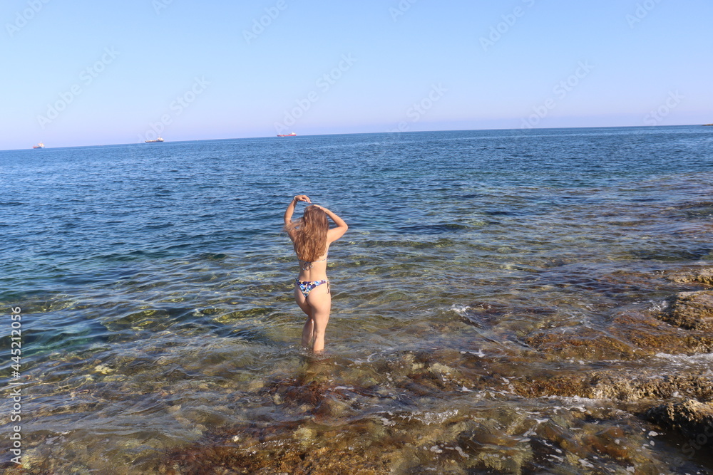 Young brunette girl on rocks beach in Malta, untouched nature