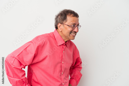 Middle aged indian man isolated on white background laughs happily and has fun keeping hands on stomach. © Asier