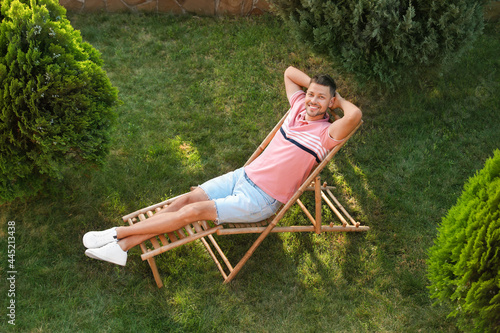 Happy man resting in deck chair outdoors, above view