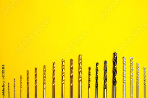 Set of drills for wood  metal and concrete on a yellow background.