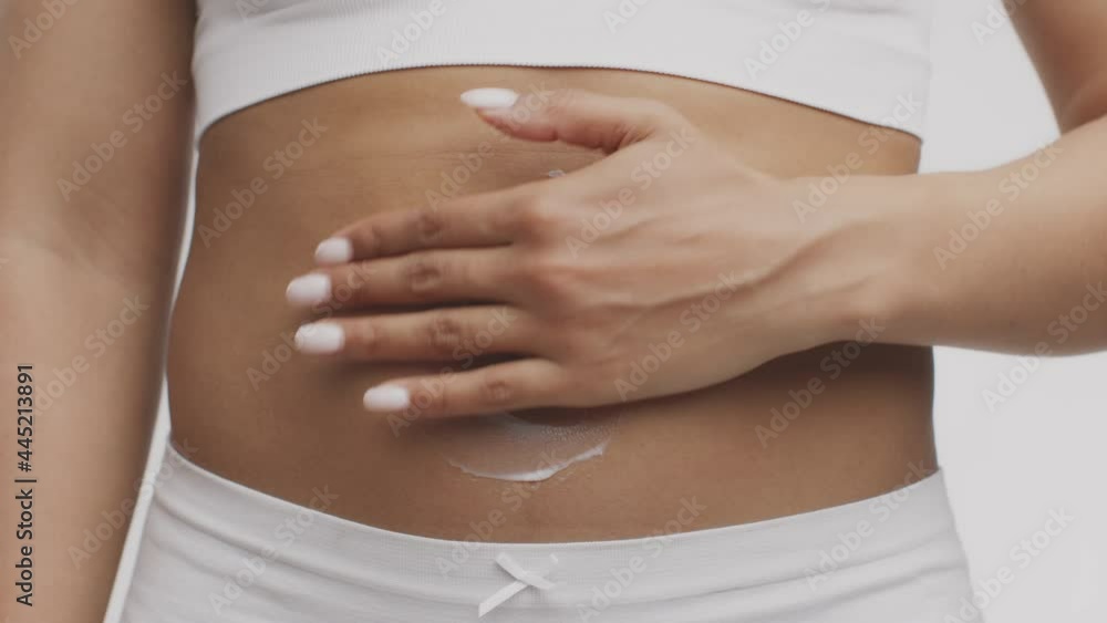 Skin lifting cosmetics, self body care concept. Unrecognizable african american lady rubbing pampering cream on belly