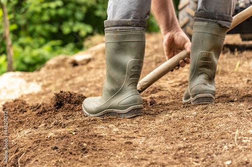 a person in boots digging in the garden; gardening